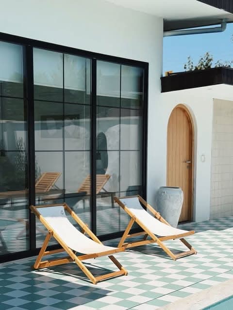 حیاط روشن The Nest با صندلیهای چوبی کنار استخر